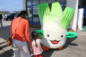 まこもたけ販売所でお客様とハイタッチするまこりん